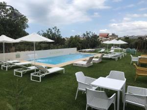 a pool with white chairs and tables and umbrellas at Kallimento in Kissamos