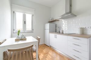 a kitchen with white cabinets and a white refrigerator at Casas da Praia by Aqualeisure in Furadouro