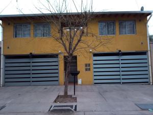 a yellow building with two garage doors and a tree at Los Nietos hospedaje in Mendoza