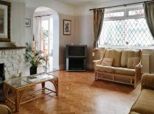 a living room with a couch and a tv at Plas Tirion in Llanddulas