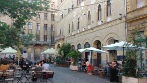 un gruppo di persone seduti ai tavoli fuori da un edificio di Palace Residence a Budapest