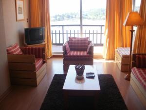 sala de estar con sofá, sillas y TV en La Peninsula Rehue, en Pucón