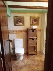 a bathroom with a toilet and two pictures on the wall at Casa Tiretes in Morella +19 photos