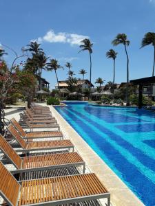 ein Swimmingpool mit Liegestühlen und Palmen in der Unterkunft Apartamento Taíba Beach Resort in Taíba