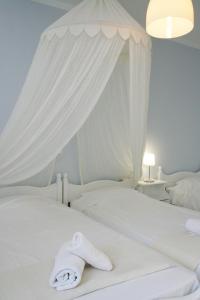 Una cama blanca con sábanas blancas y toallas. en Studios Eleni I, en Tinos