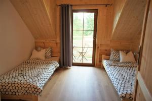 two beds in a room with a window at Przystań Bieszczady in Zawóz