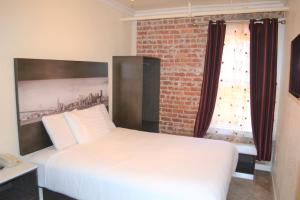 a bedroom with a white bed and a brick wall at Inn on Folsom in San Francisco