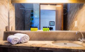 a bathroom with a sink and a mirror and towels at Apollonia Hotel Apartments in Varkiza
