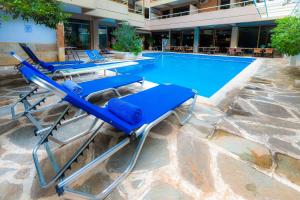 a row of blue lounge chairs next to a swimming pool at Apollonia Hotel Apartments in Varkiza