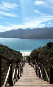 un paseo marítimo de madera que conduce a la playa y al océano en Flat da Natasha, en Arraial do Cabo