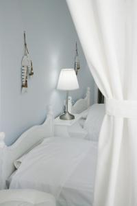 a white bedroom with two beds and a lamp at Studios Eleni I in Tinos