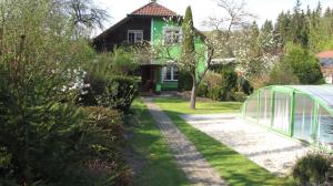 a garden with a greenhouse in front of a house at Penzion Šárka in Karlovy Vary