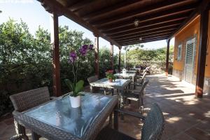 un patio al aire libre con mesas, sillas y flores púrpuras en B&B Villa Eleonora, en Realmonte