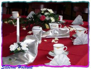 a red table with white cups and saucers and flowers at Landgasthof Sonneneck in Listerfehrda