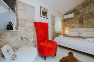 Un dormitorio con una silla roja y una cama en Apartment Toma, en Trogir