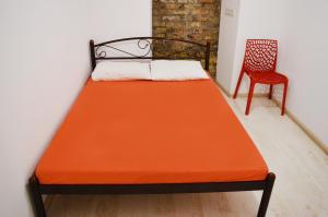 a bed with an orange sheet and a chair at Hostel Train Station in Kyiv
