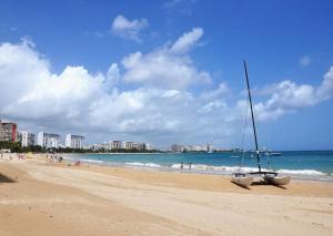 a sailboat on a beach with people in the water at Non Stop party Apartment Condo in San Juan