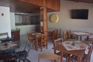 a dining room with tables and chairs and a tv at Pousada Vida Boa in Cabo Frio