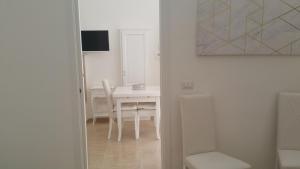 a white dining room with a white table and chairs at Suite Pitagora in Bernalda +13 photos
