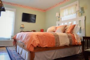a bedroom with a large bed with an orange comforter at Hawksbill House - (Adults Only) in Luray