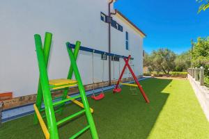 a yard with a playground with swings at Villa Marivel in Privlaka