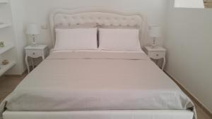 a bedroom with a white bed with two night stands at Suite Pitagora in Bernalda