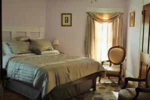 a bedroom with a bed and a chair and a window at Hawksbill House - (Adults Only) in Luray