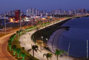 una calle con palmeras junto al océano por la noche en Praia Comprida Hotel, en São José