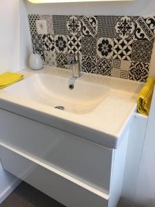 lavabo blanco en el baño con azulejos blancos y negros en Le Coin Cocoon Bis, en Aywaille
