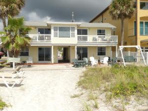 a house on the beach with chairs and palm trees at Sand Glo Villas in Clearwater Beach +102 photos