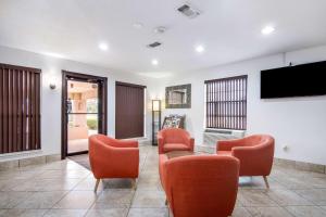 a living room with orange chairs and a flat screen tv at Motel 6-Marshall, TX in Marshall
