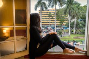 a woman sitting on a window sill looking out at Flying Dog Hostel in Lima