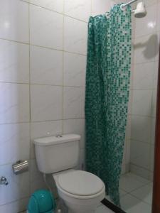 a bathroom with a toilet and a green shower curtain at Itaipuaçu Residencia Cajueiros I in Itaipuaçu +20 photos