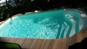 uma piscina com água azul e um deque de madeira em T2 KAY ZANNDOLI em La Trinité