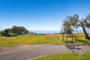 an empty road in a park with the ocean in the background at NRMA Phillip Island Beachfront Holiday Park in Cowes