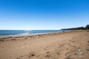 a beach with footprints in the sand and the ocean at NRMA Phillip Island Beachfront Holiday Park in Cowes