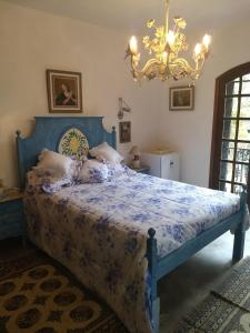 een blauw bed in een slaapkamer met een kroonluchter bij Suites em meio a Mata Atlântica in Itaipava