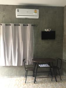 a table and two chairs in a room with a curtain at เจิดจรัสรีสอร์ทโรงแรม24ชม in Chon Buri
