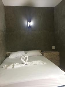 a bed with two towels on it with two lights at เจิดจรัสรีสอร์ทโรงแรม24ชม in Chon Buri