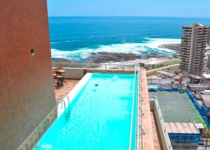 a swimming pool with the ocean in the background at Gran Cavancha Hotel & Apartment in Iquique