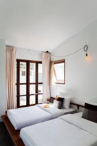 two beds in a room with two windows at Krodyle Mindfulness House in Phra Nakhon Si Ayutthaya