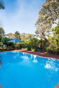 a large blue swimming pool with an umbrella at Guildford River Retreat in Perth