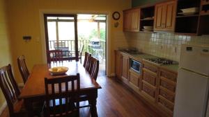 a kitchen with a wooden table and a table and chairs at The Blue House Yungaburra in Yungaburra