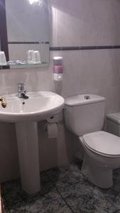 a bathroom with a white toilet and a sink at Hotel El Marino in Santiago de la Ribera