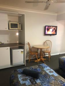 a room with a bed and a table and a microwave at Breeze Inn 13 Princes Highway, Ulladulla in Ulladulla