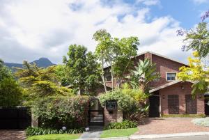 a brick house with trees and bushes at Aziza Guest House in George