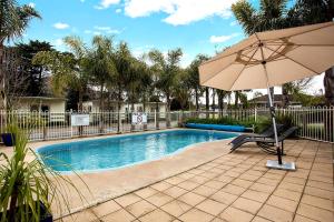 a swimming pool with a chair and an umbrella at Lake Hamilton Motor Village and Caravan Park in Hamilton