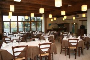 un restaurante con mesas y sillas blancas y ventanas en Hotel Magnolia en Comacchio
