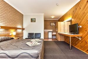 a hotel room with a bed, desk and television at Holbrook Town Centre Motor Inn in Holbrook