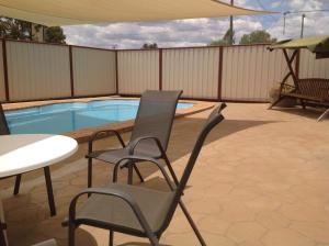 a patio with two chairs and a table and a pool at Charleville Waltzing Matilda Motor Inn in Charleville